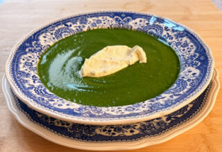 Spinach, leek and potato soup with whipped lemon cream in a blue-and-white bowl